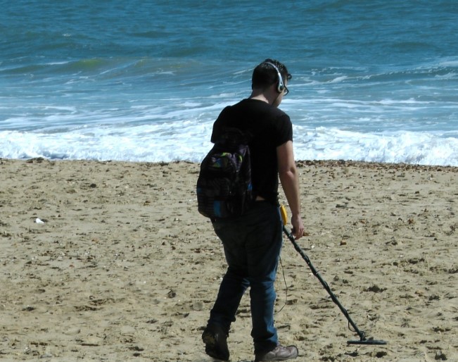 Man on the beach holding a metal detector